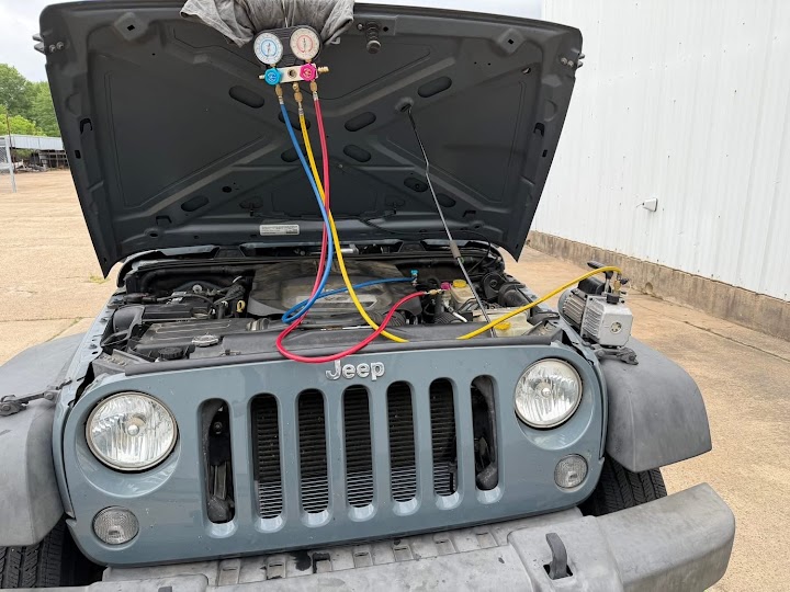 Technician working under the hood of a vehicle at the curb
